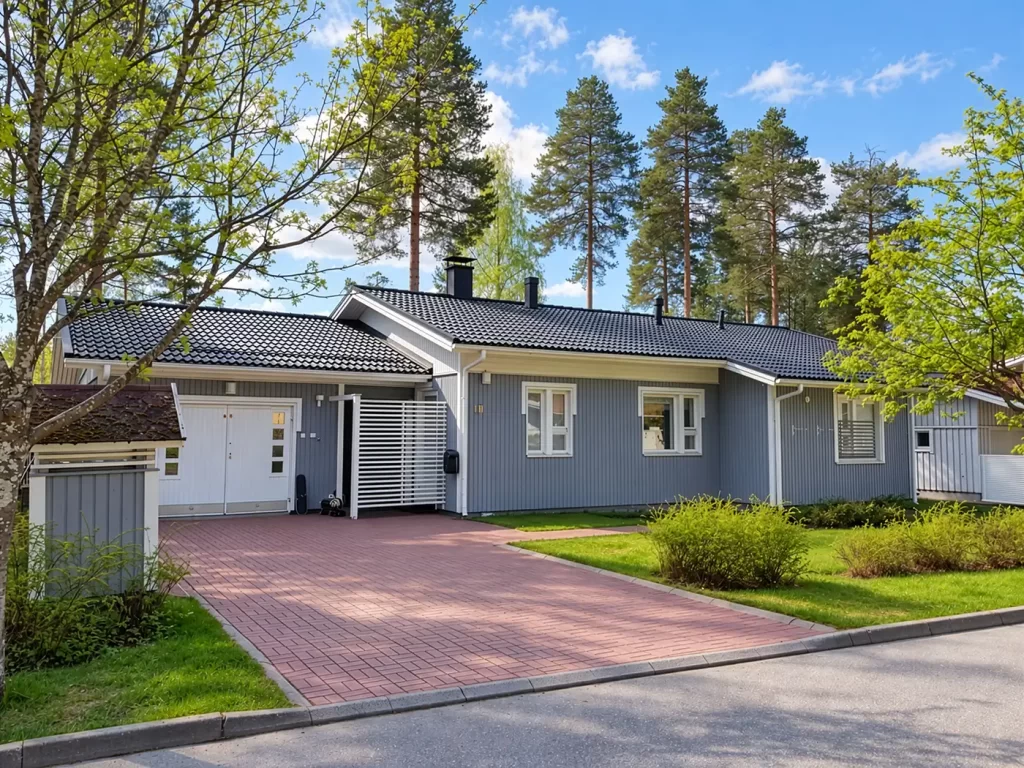 Harmaaksi maalattu puuverhoiltu omakotitalo valkoisine ikkunanpielineen ja räystäslautoineen.