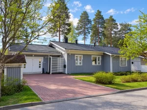Harmaaksi maalattu puuverhoiltu omakotitalo valkoisine ikkunanpielineen ja räystäslautoineen.